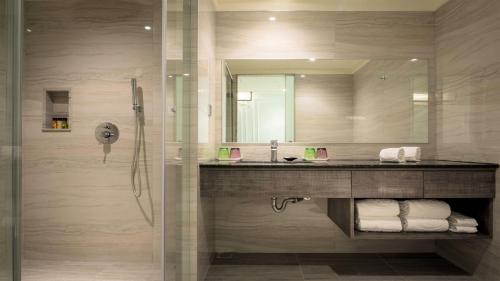 a bathroom with a sink and a shower with a mirror at Sun Hao Hotel Taichung in Taichung