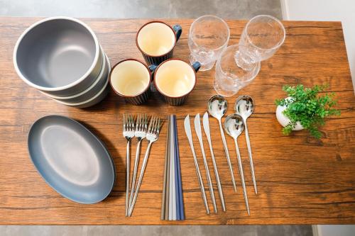 a wooden table with plates and forks and wine glasses at Seaside Tamachi by Tranova in Tokyo