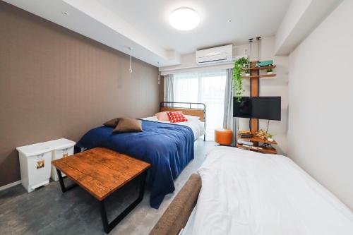 a bedroom with two beds and a table and a tv at Seaside Tamachi by Tranova in Tokyo
