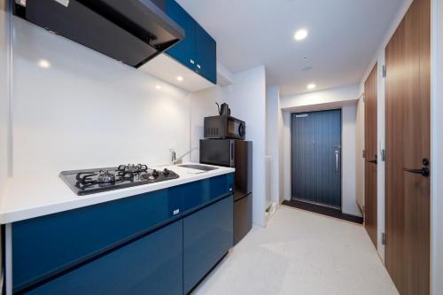 a kitchen with blue cabinets and a refrigerator at Seaside Tamachi by Tranova in Tokyo
