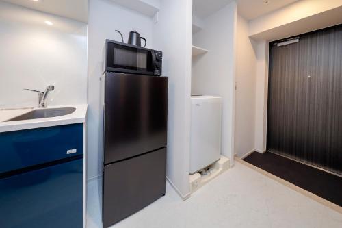 a kitchen with a refrigerator with a microwave on top at Seaside Tamachi by Tranova in Tokyo