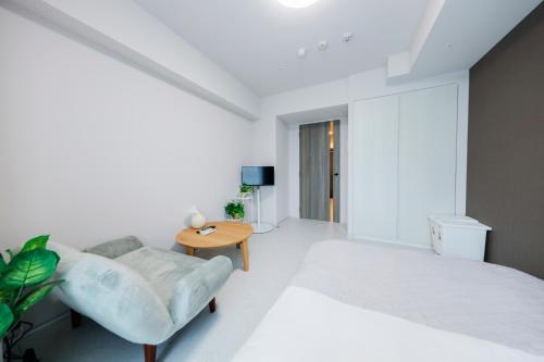 a white bedroom with a bed and a table at Seaside Tamachi by Tranova in Tokyo