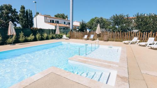 a swimming pool with chairs and umbrellas in a yard at Camping La Prée in Les Portes