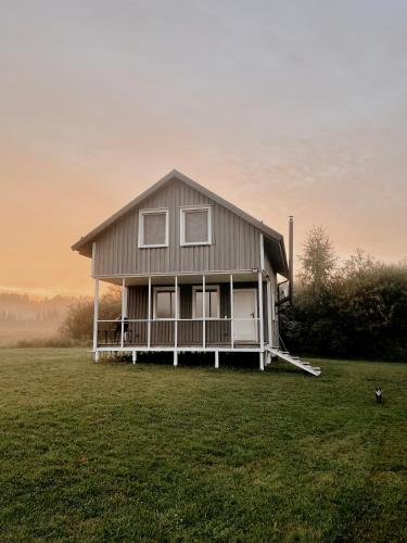 uma casa sentada em cima de um campo de relva em HYGGE Sauna&Fishing House 