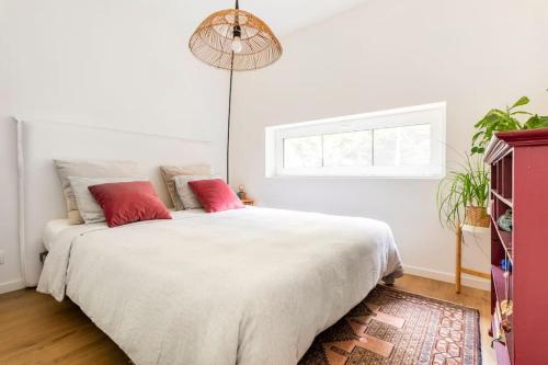1 dormitorio con 1 cama blanca grande con almohadas rojas en Luxe-Avontuur in een Romantische Cabin in het Bos, en Stekene