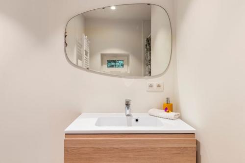 ein Bad mit einem Waschbecken und einem Spiegel in der Unterkunft Luxe-Avontuur in een Romantische Cabin in het Bos in Stekene