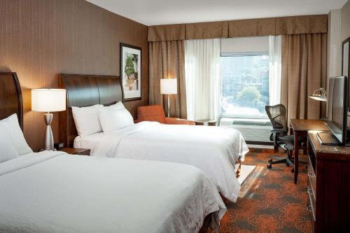 a hotel room with two beds and a desk and a window at Hilton Garden Inn Seattle Downtown in Seattle