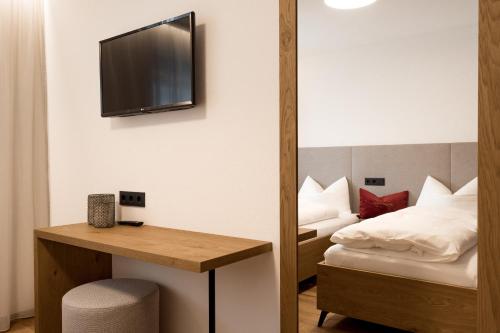a hotel room with a bed and a tv on the wall at Obergasserhof Apt Tiroler in Riscone