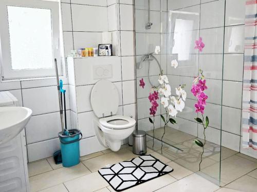 a bathroom with a toilet and flowers on the floor at Work & Stay in Mannheim in Mannheim