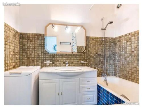a bathroom with a sink and a tub and a mirror at Appartement la Galerne Royan-Pontaillac - plage casino in Vaux-sur-Mer