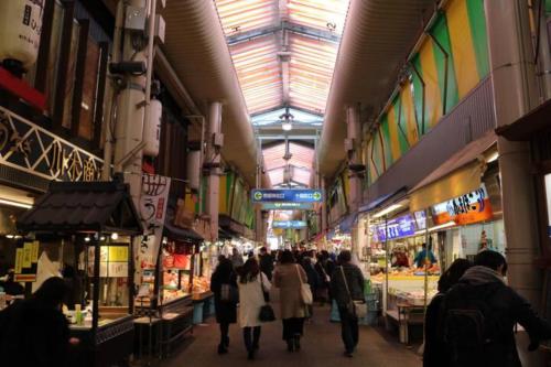 um grupo de pessoas caminhando através de um mercado em marutto Ishikawa em Kanazawa