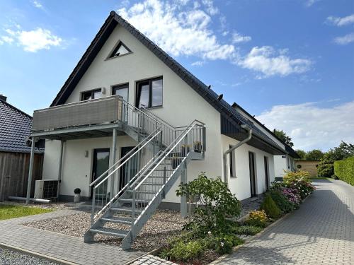 ein weißes Haus mit einer Treppe davor in der Unterkunft Ferienwohnung Lubmin VORP 2952 in Lubmin