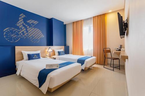 a hotel room with two beds and a blue wall at Arte Hotel Yogyakarta in Yogyakarta