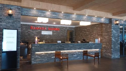 a restaurant with two chairs and a bar with a brick wall at Ramada by Wyndham Suanbo in Chungju
