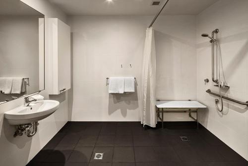 a white bathroom with a sink and a shower at Quest Bella Vista in Baulkham Hills