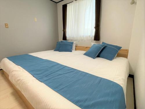 1 dormitorio con 1 cama grande con almohadas azules en Portside美崎町 離島ターミナル徒歩3分 室内リニューアルOPEN en Isla Ishigaki