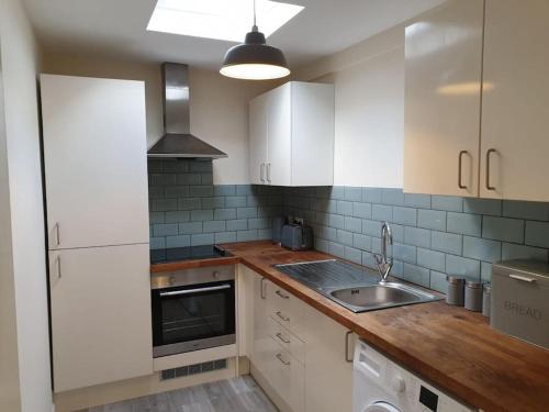 a kitchen with white cabinets and a sink at Two Bed Flat Sea view Old town Hastings in Hastings