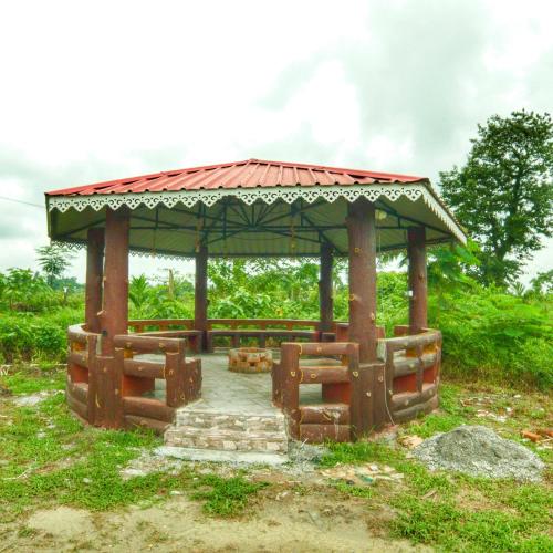 a wooden gazebo in a grassy field at The GreyStone FarmHouse, Turibari in Ranīchera