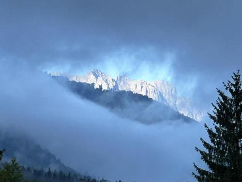 Blick auf eine Bergkette mit Wolken und Bäumen in der Unterkunft Gästehaus Wiesegg in Reit im Winkl