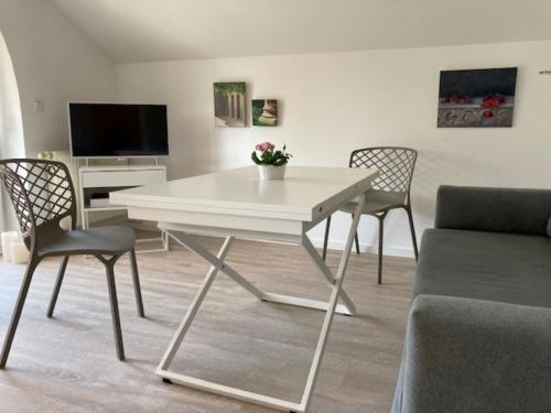 einen weißen Tisch und Stühle im Wohnzimmer in der Unterkunft Kleine Galerie in Schönberger Strand