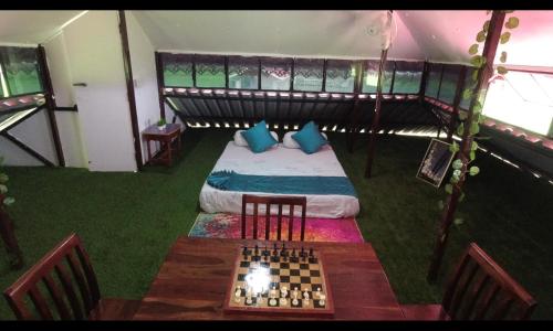 a room with a bed and a chess board on a table at The GreyStone FarmHouse, Turibari in Ranīchera