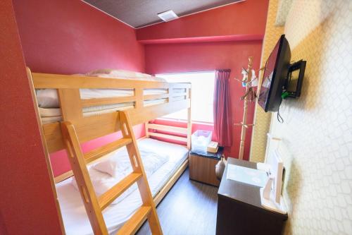Pokój z 2 łóżkami piętrowymi i telewizorem w obiekcie Hiroshima Wabisabi hostel 広島ワビサビ ホステル w mieście Hiroszima