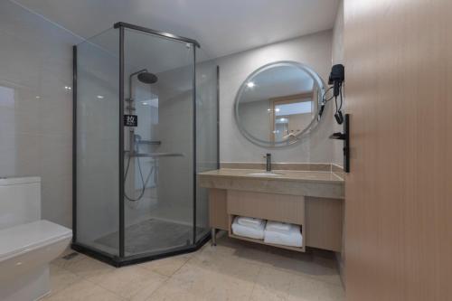 a bathroom with a shower and a sink and a mirror at Chengdu Bai Gang International Hotel in Chengdu