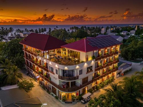 une vue aérienne d'un bâtiment avec un coucher de soleil en arrière-plan dans l'établissement Araamu Holidays & Spa, à Dhiffushi