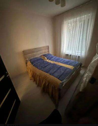 a bedroom with a bed with a blue comforter and a window at Kirovakan Vacation House in Vanadzor