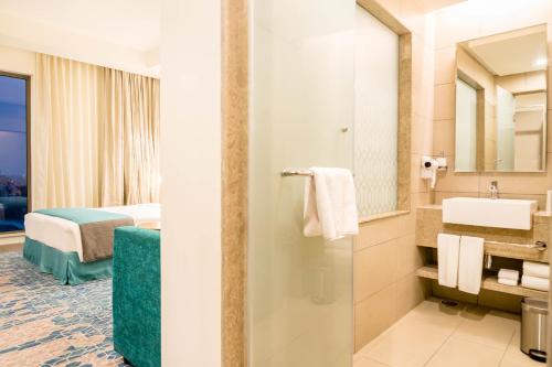 a hotel room with a bathroom with a sink and a bed at Holiday Inn Express Kolkata Airport, an IHG Hotel in Kolkata