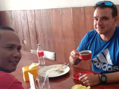 zwei Männer sitzen an einem Tisch mit einem Glas Wein in der Unterkunft Hotel Mexico Berastagi in Berastagi