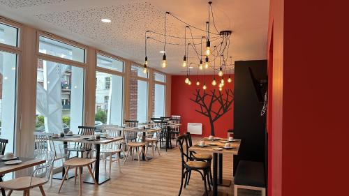 a dining room with tables and chairs and windows at Nemea Appart Hotel Coliseum Amiens Centre in Amiens