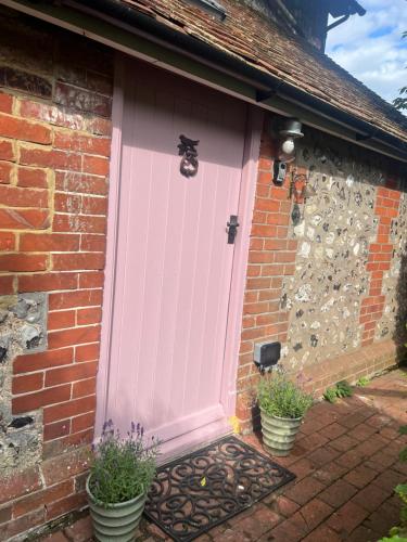 a pink door on the side of a brick house at The Snug at Littledown in Lewes