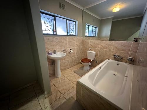 a bathroom with a tub and a toilet and a sink at Cornerstone Guest House in Polokwane