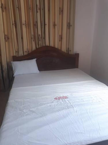 a bed with white sheets and a wooden head board at Nhà nghỉ 99 