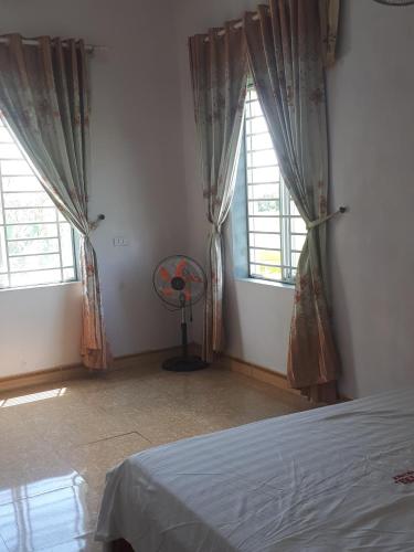 a bedroom with two windows and a fan in it at Nhà nghỉ 99 