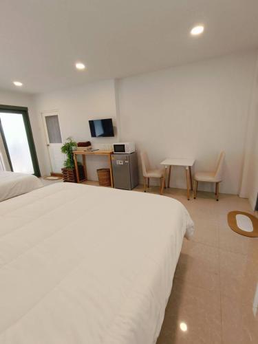 a bedroom with a white bed and a table and chairs at บ้านสุขใจ อัมพวา in Samut Songkhram