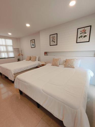 2 camas en una habitación con paredes blancas en บ้านสุขใจ อัมพวา, en Samut Songkhram