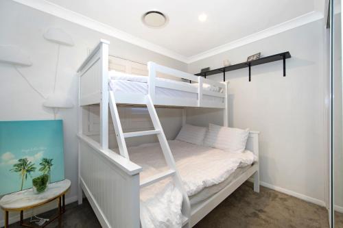 a white bunk bed with a ladder in a room at Woy Woy Staycation - Heated Pool & Hot Tub & BBQ & Pizza Oven & Arcade Game & Pool Table in Woy Woy