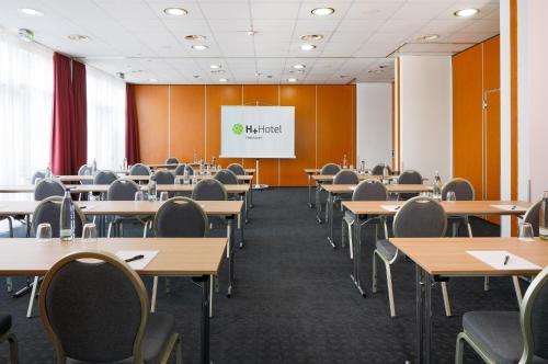 an empty classroom with tables and chairs and a whiteboard at H+ Hotel Hannover in Hannover