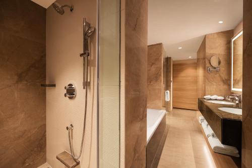 a bathroom with a shower and a tub and a sink at Hyatt Place Vijayawada in Vijayawāda
