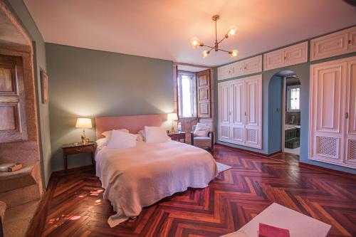una camera con letto bianco e pavimento in legno di Pazo del siglo XVII en el corazón de Galicia a Lalín