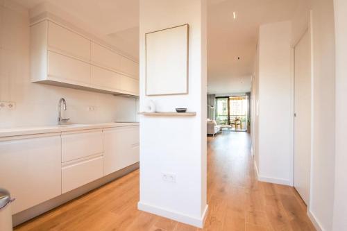 uma cozinha branca com armários brancos e piso em madeira em Longbeach Smart Muchavista em Alicante