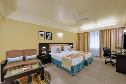 VernaにあるThe Fern Kesarval Hotel & Spa, Verna Plateau - Goaのベッドとソファ付きのホテルルーム