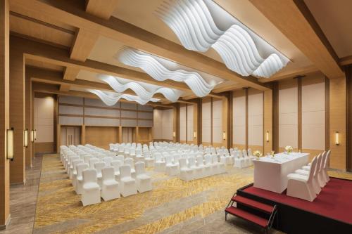 a banquet hall with white tables and white chairs at Hyatt Place Vijayawada in Vijayawāda