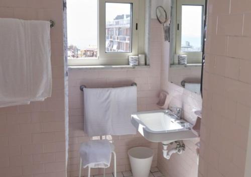 W białej łazience znajduje się umywalka i lustro. w obiekcie Hotel Del Golfo w mieście Formia
