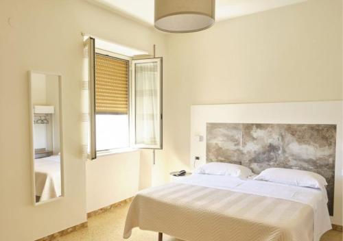 biała sypialnia z łóżkiem i lustrem w obiekcie Hotel Del Golfo w mieście Formia