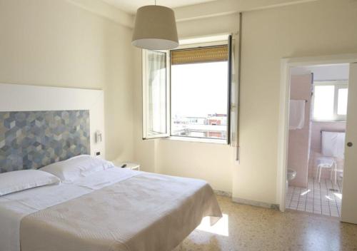 a bedroom with a large white bed and a window at Hotel Del Golfo in Formia