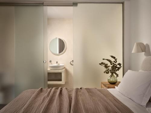a bedroom with a bed with a sink and a mirror at Azera Suites in Alikanas