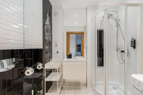 a white bathroom with a shower and a sink at Modern Apartment with FREE parking spot in Kraków